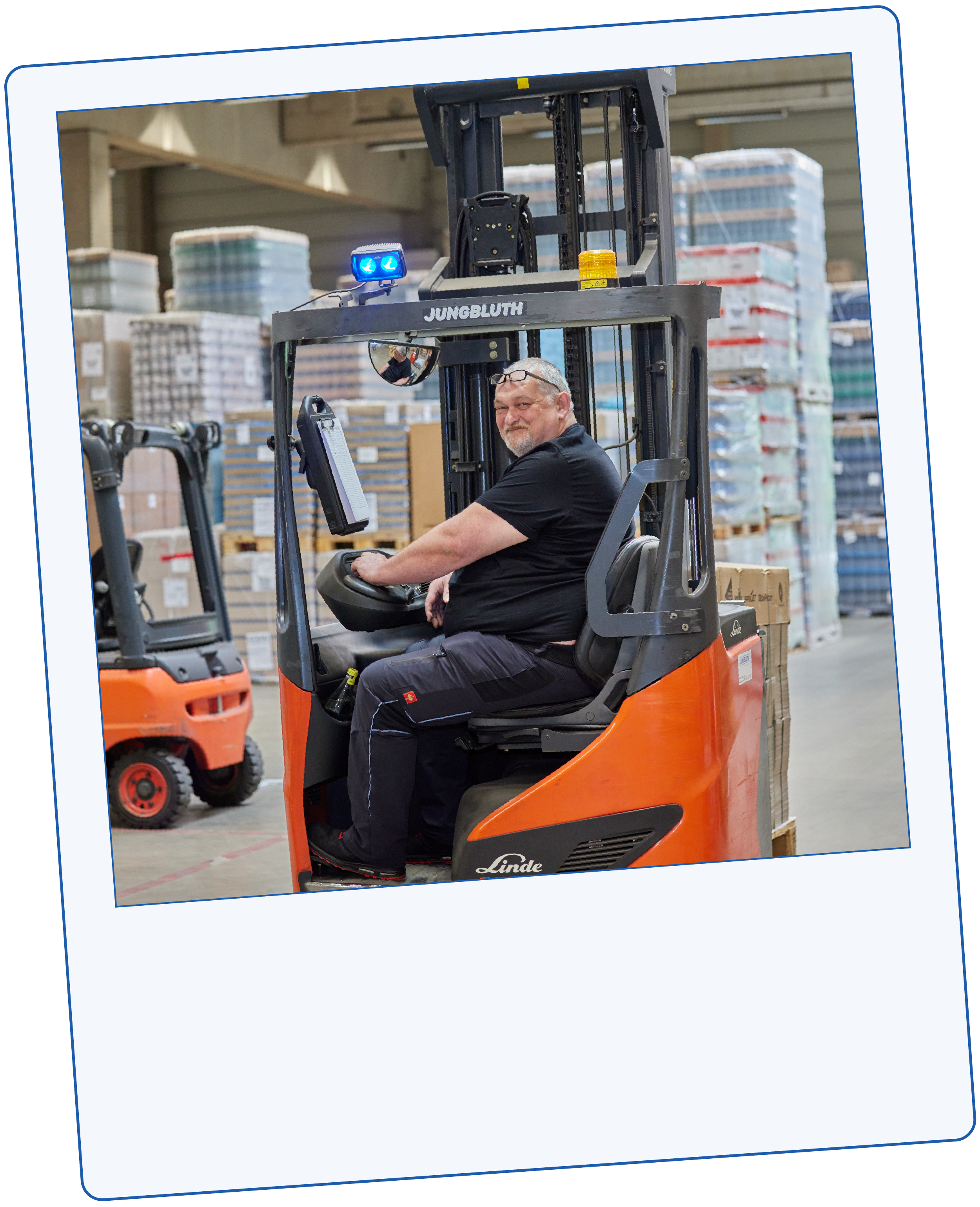 Lächelnder Mann sitzt in einem Gabelstapler in einer Lagerhalle